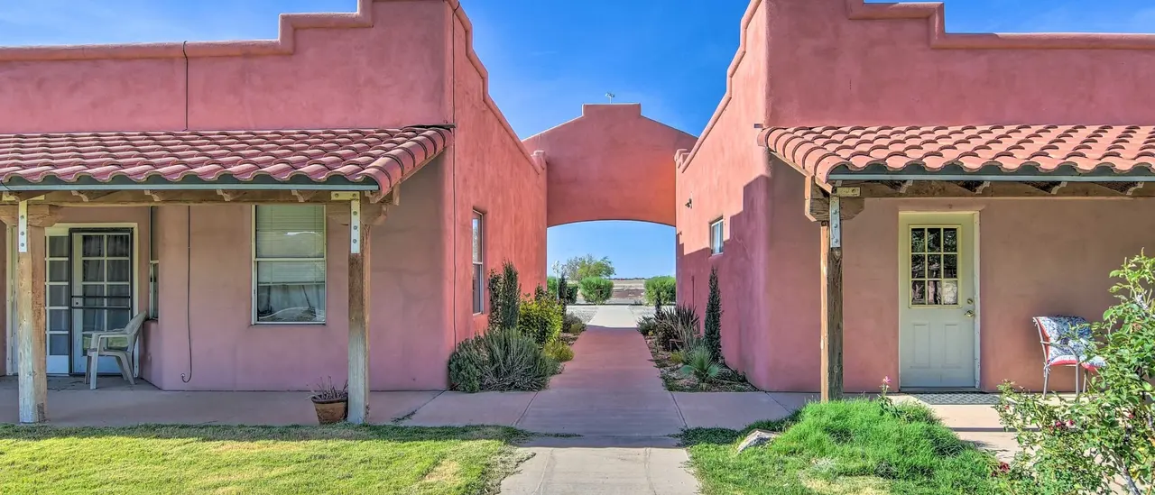 Two rose-colored casas joined by an arch over a garden walk