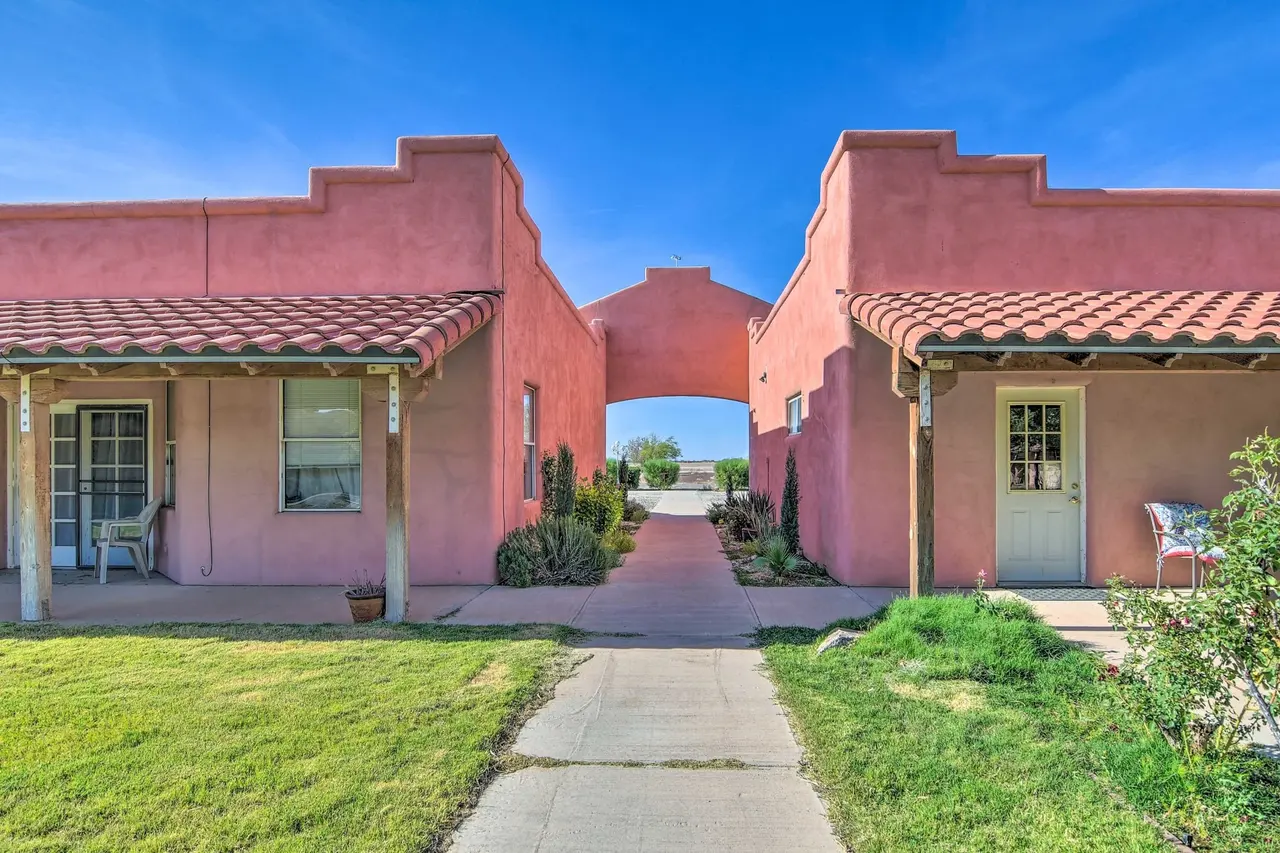 Two rose-colored casas joined by an arch over a garden walk