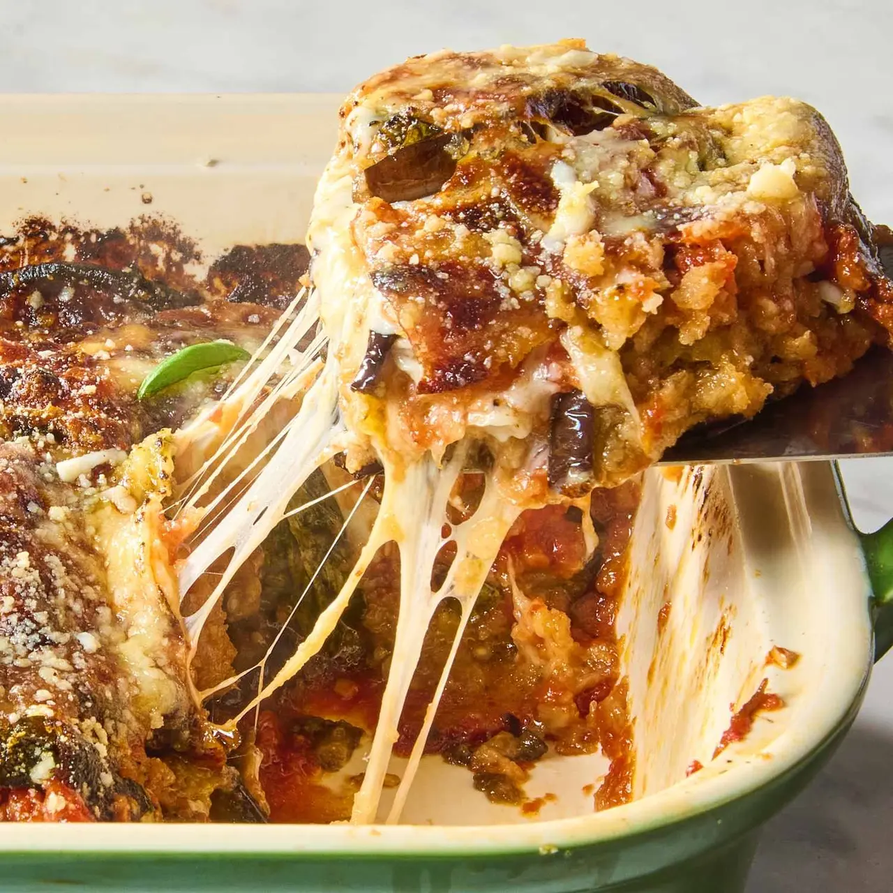 A serving of bubbling eggplant parmesan lifted from the baking dish