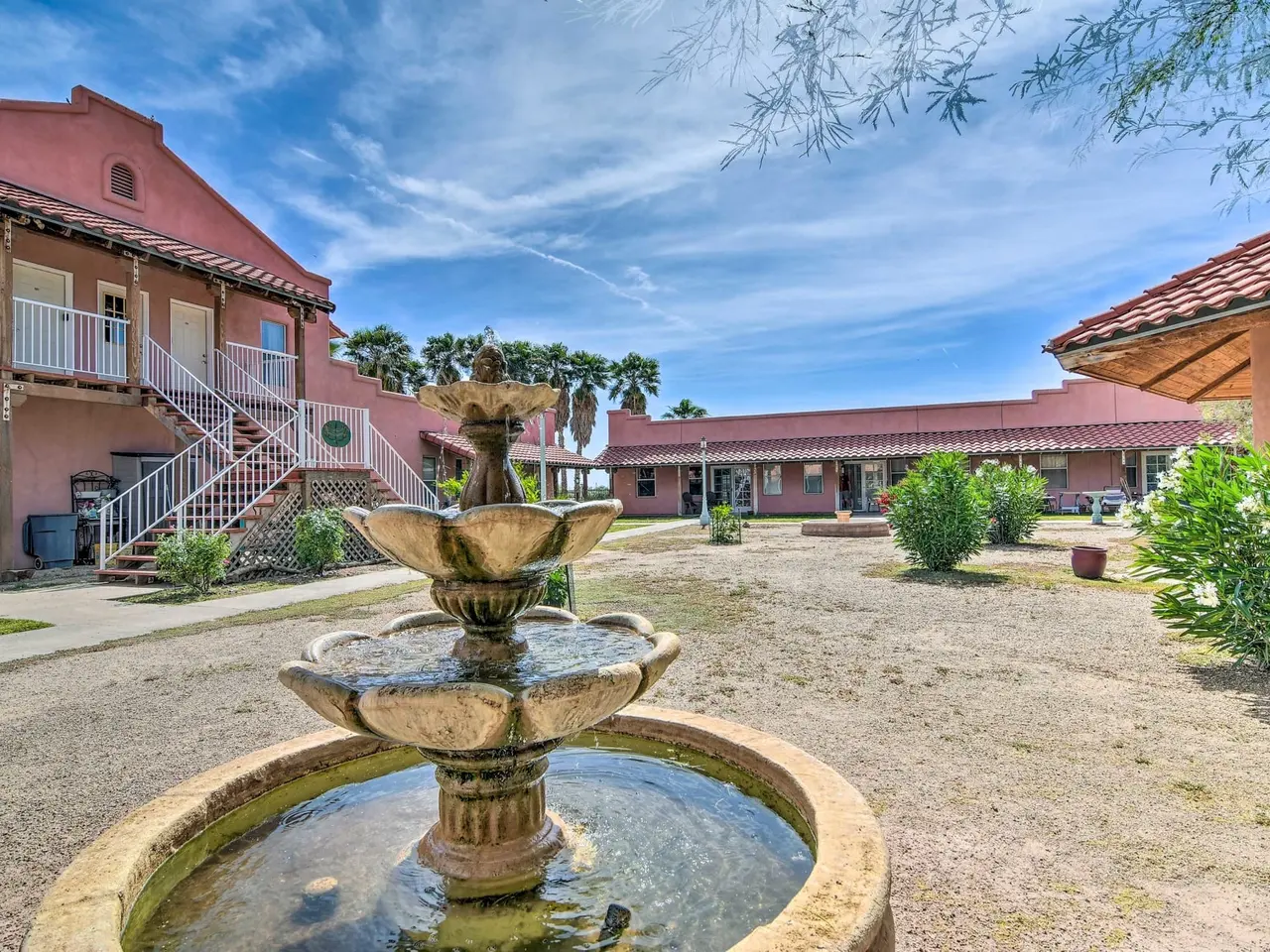 A tiered fountain in the casa courtyard beneath a two-story adobe wing