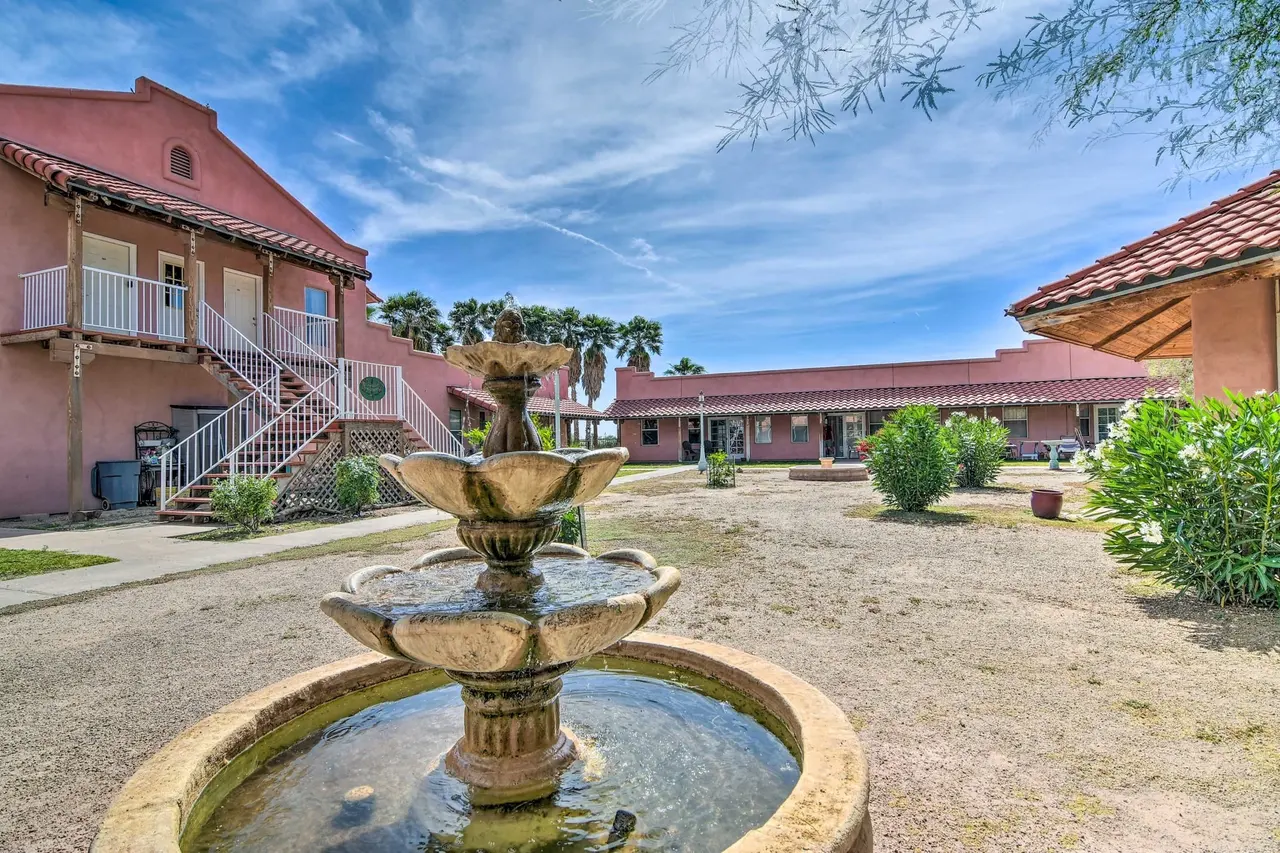 A tiered fountain in the casa courtyard beneath a two-story adobe wing