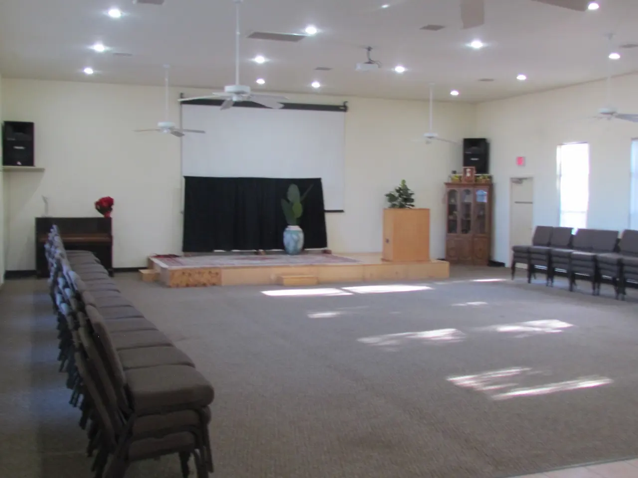 Hall set with chairs facing a low stage and projection screen