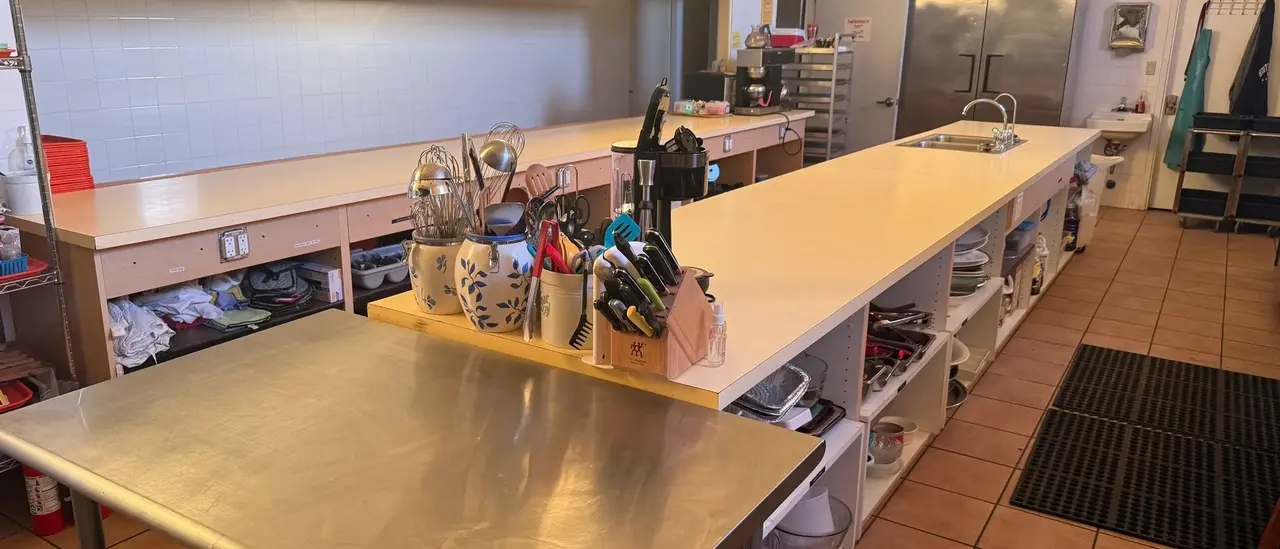 Commercial kitchen with a long stainless prep table and walk-in refrigeration
