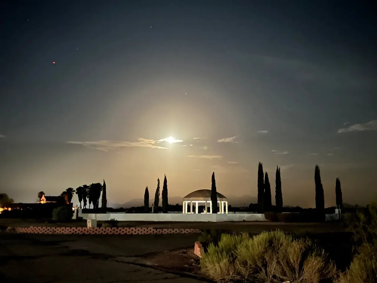 Moonlight over the desert and a distant lit pavilion