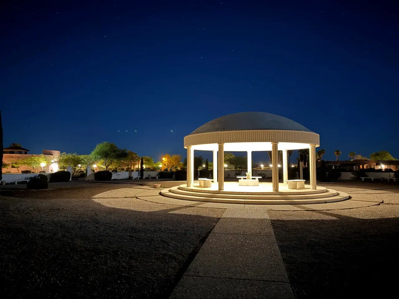 The lit pavilion at the end of a long walk under a deep blue night sky